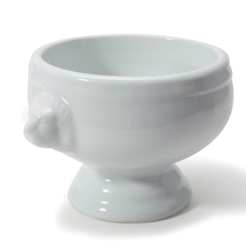 A white porcelain soup bowl with a lion's head design on the side, on a plain background.