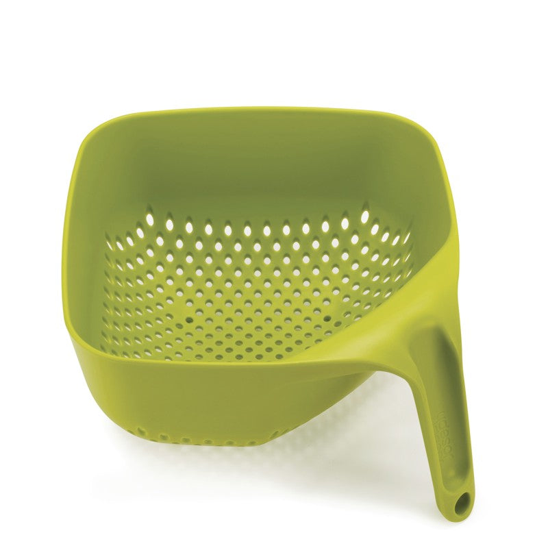A green Joseph Joseph Square Stackable Colander with square holes for draining.